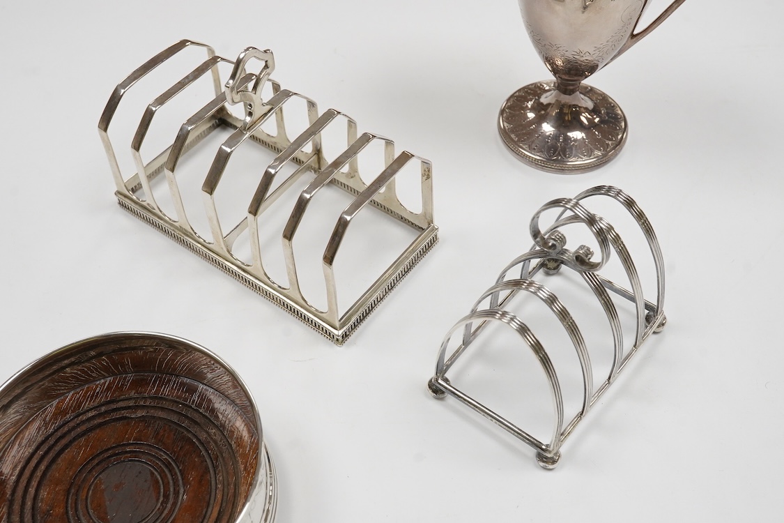 A George III engraved silver helmet shaped cream jug, Henry Chawner, London 1788(repair), height 15.3cm, together with two George V silver toast racks, a silver mounted glass toilet jar and a modern silver mounted bottle